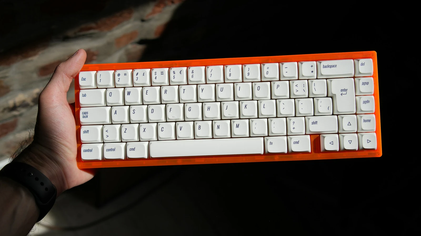 Person holding a compact mechanical keyboard above a desk