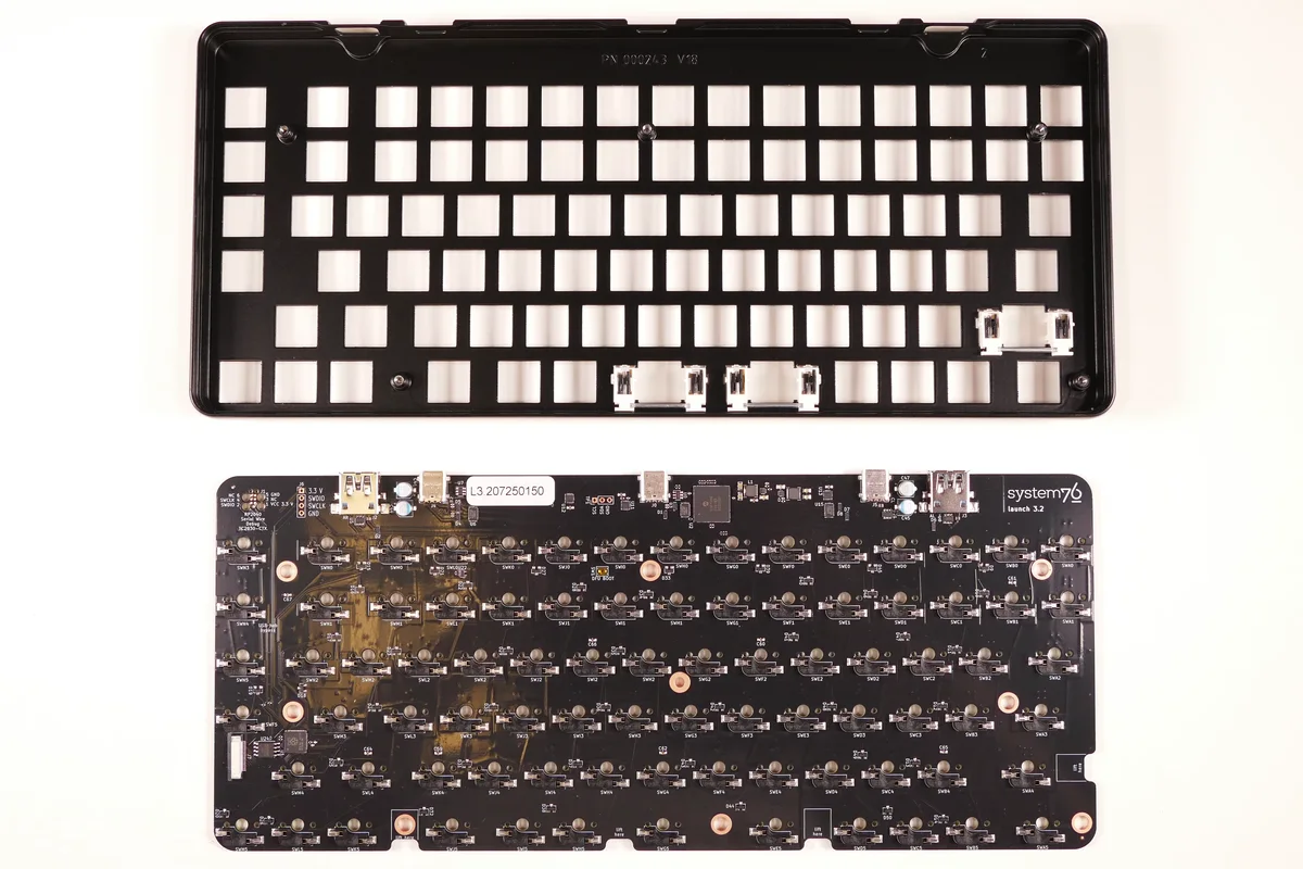 Bare custom-keyboard PCB and switch plate laid out for inspection before assembly