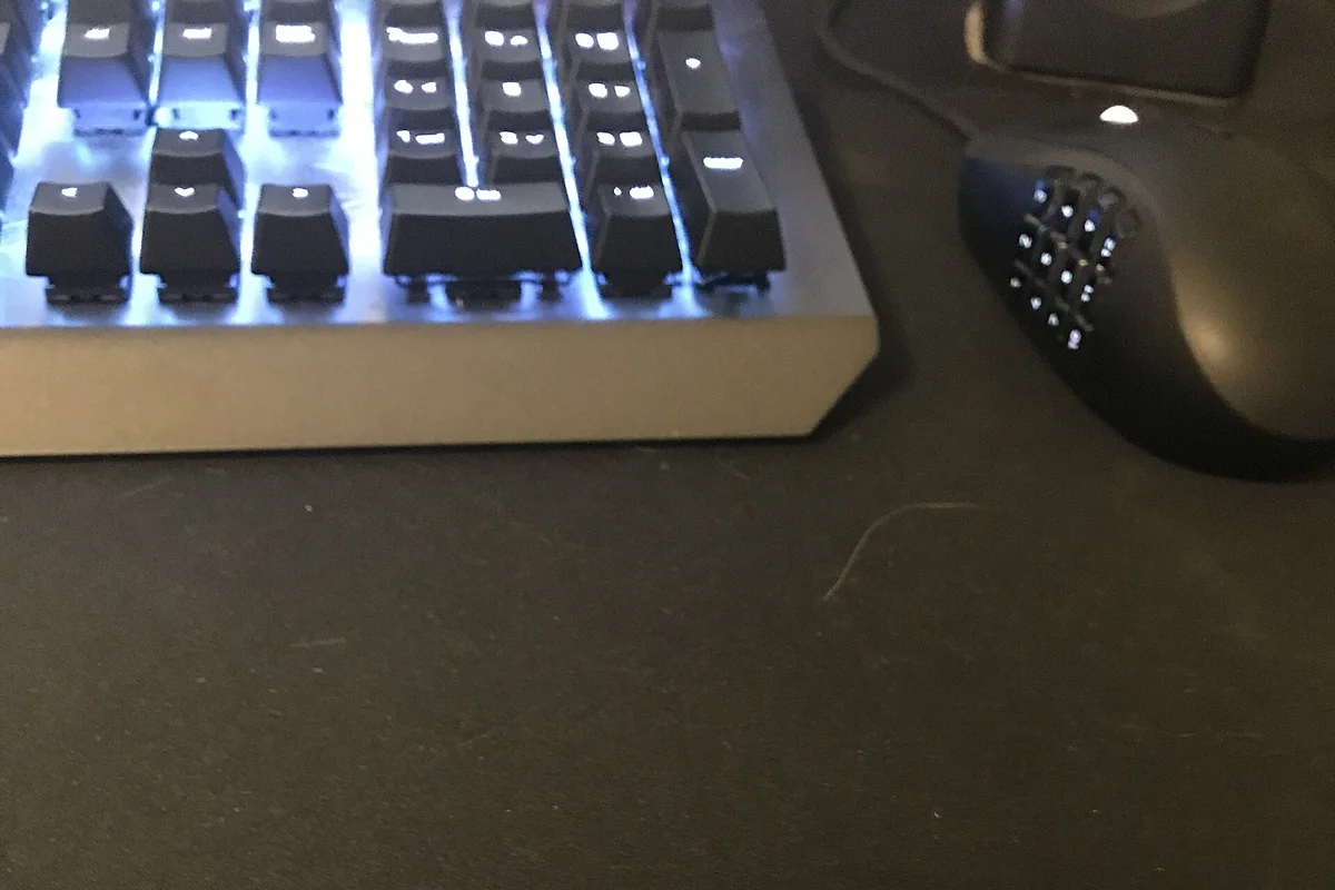 Keyboard and mouse resting on a large dark desk mat