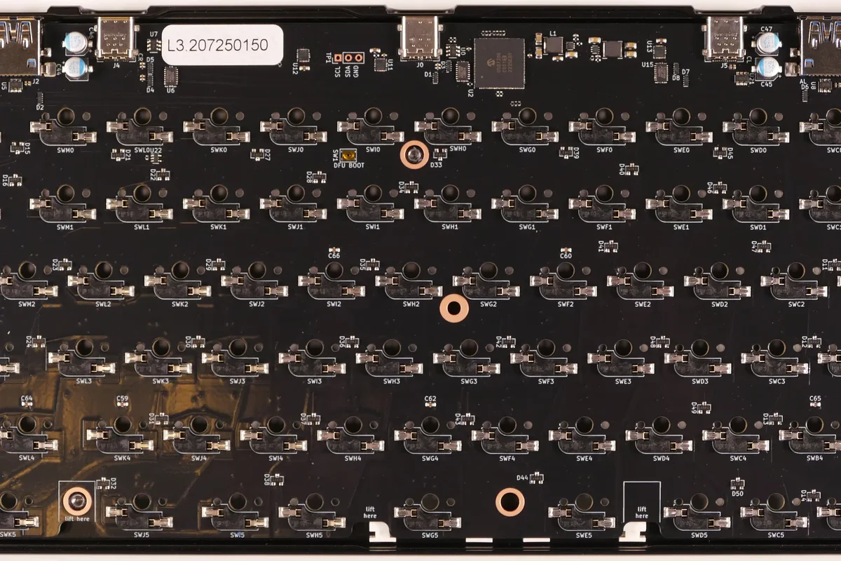 Open keyboard viewed from below, showing the PCB sockets, screw posts, ports, and components that case foam must clear