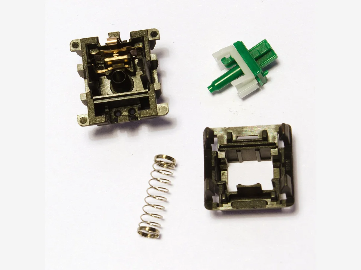 Disassembled mechanical switch with housing, stem, and spring separated for careful lubrication