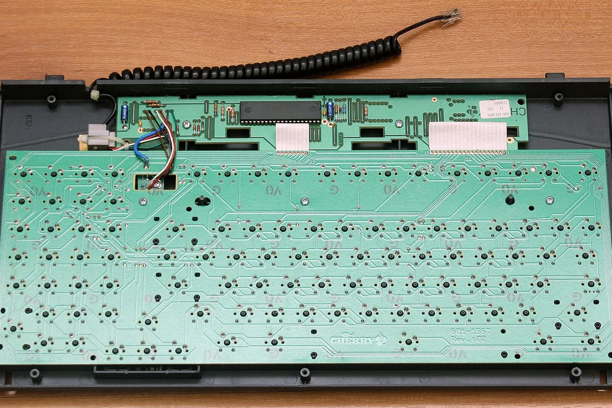 Back of a wired keyboard PCB with screw holes, connectors, and components left visible