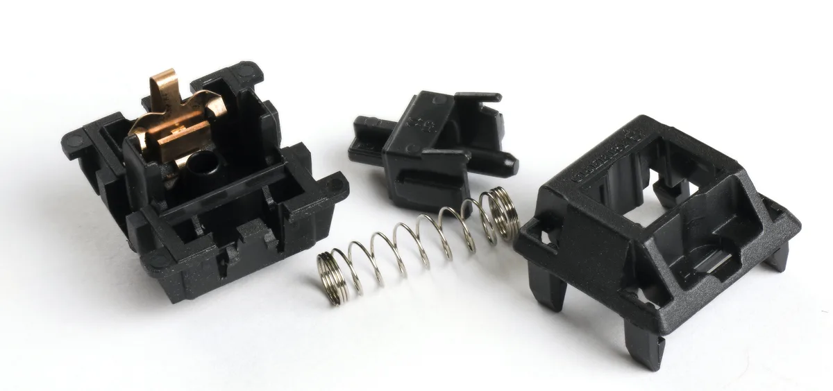 Disassembled linear switch showing the stem, spring, contact leaf, and upper and lower housings
