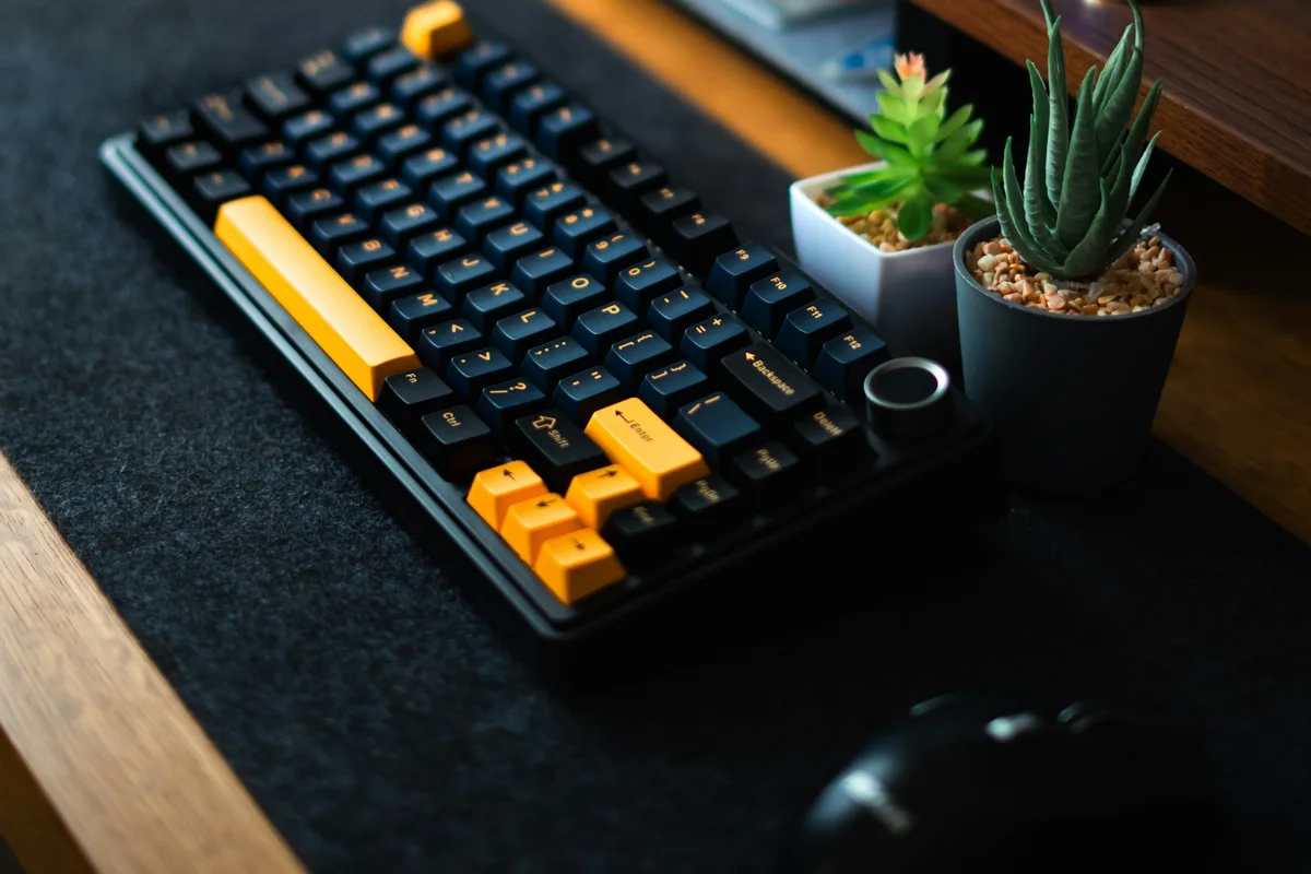 A compact 75% keyboard beside a mouse, leaving open movement space on a desk mat